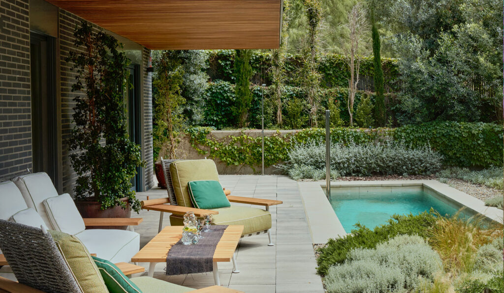 Comedor de jardín con sillas de diseño y vistas a la piscina.